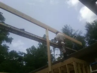 Carpenter setting a ridge beam over a new addition frame — Ice Dam Removal by Roofing Brothers in Ogema