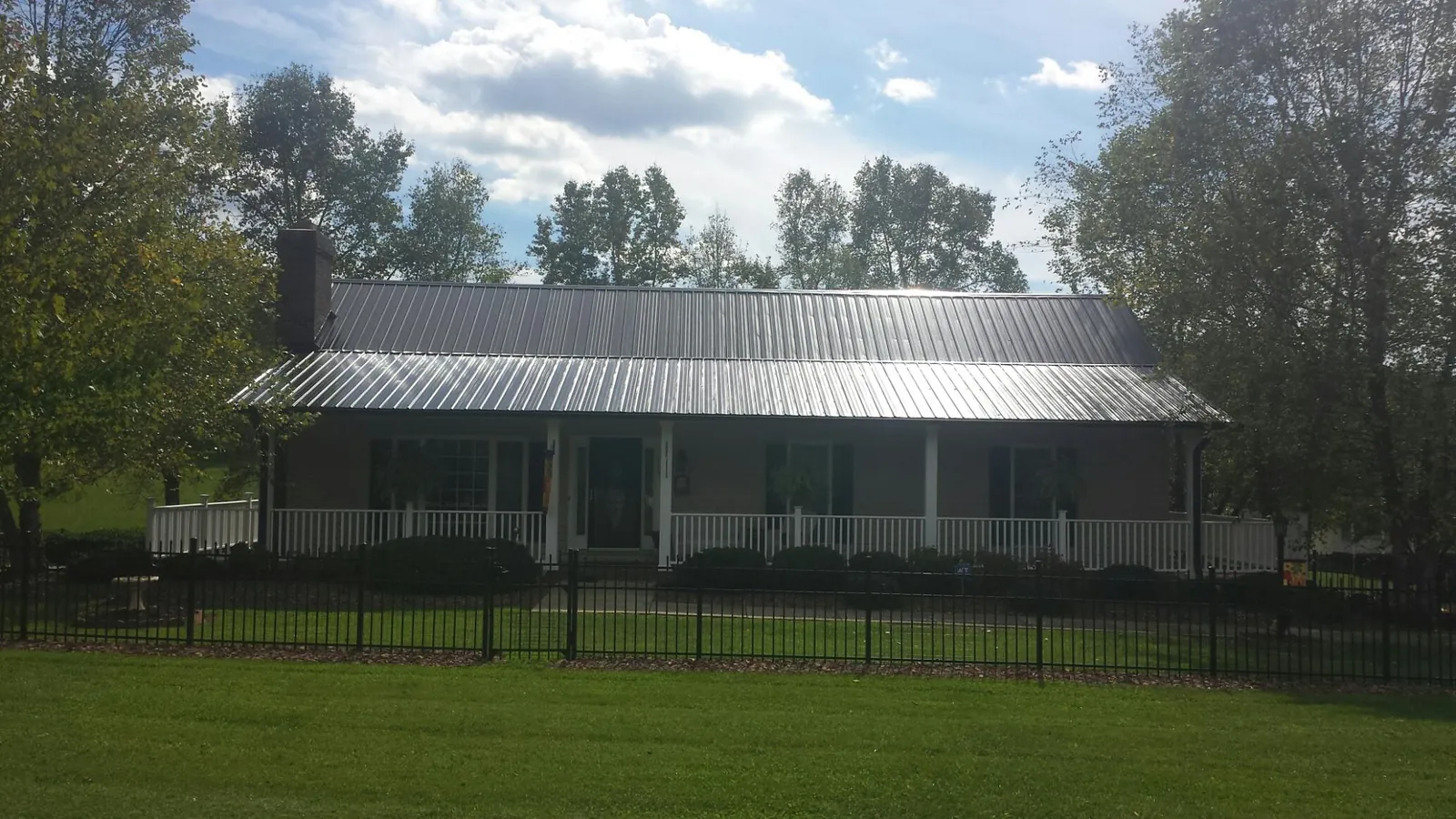 Gray metal roof on a brick ranch with a full width front porch — Gutter Guard Installation work by our crew in Ogema