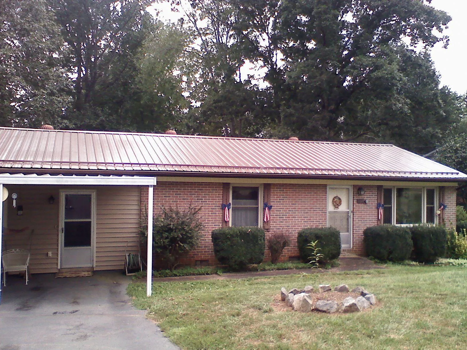 Bronze metal roof and carport on a brick ranch home — Roof Repair work by our crew in Ogema
