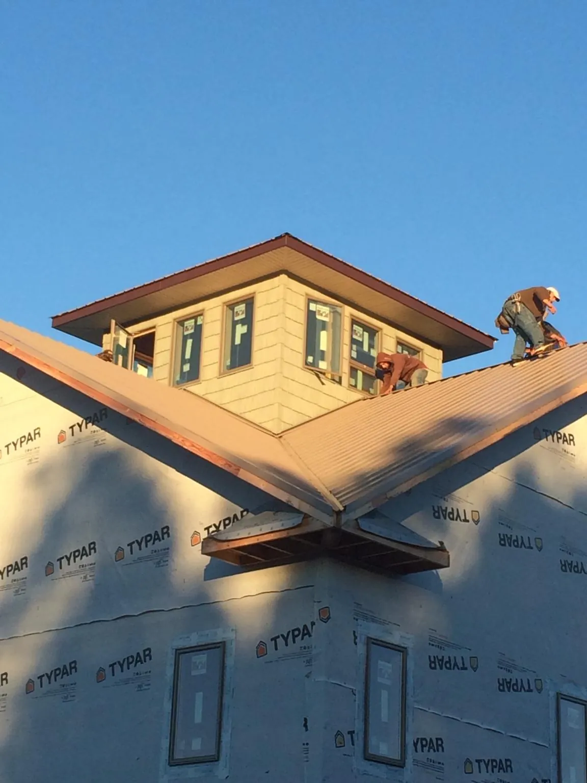 Roofers working around a rooftop cupola on a new metal roof at sunset — Roof Waterproofing in Ogema by Roofing Brothers